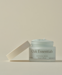 A light blue Refining Mask sits in an open glass jar labeled “Refining Mask” on a neutral background, with the lid resting at an angle beside it.