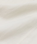 Close-up of the Callan Dress in white, featuring a smooth, slightly wrinkled fabric with soft folds. Its timeless elegance and classic style make it a true closet staple, beautifully highlighted by natural light.
