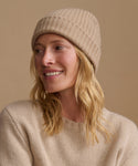 Woman wearing an oatmeal color cashmere sweater with a matching ribbed beanie.