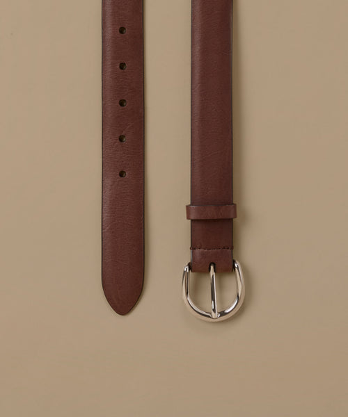 A brown leather belt shown vertically against a solid beige background, displaying both the strap end with holes and the buckle.