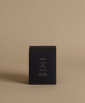 A candle box with the scent Amber across the front against a beige background.