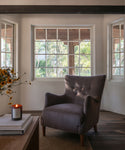 A living room setting with an accent chair, coffee table and a glass candle burning.