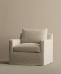 The Harbor Chair by Jenni Kayne Furniture features a modern, boxy silhouette with straight armrests, upholstered in light beige Drift Linen with plush seat and back cushions, set against a matching beige background.