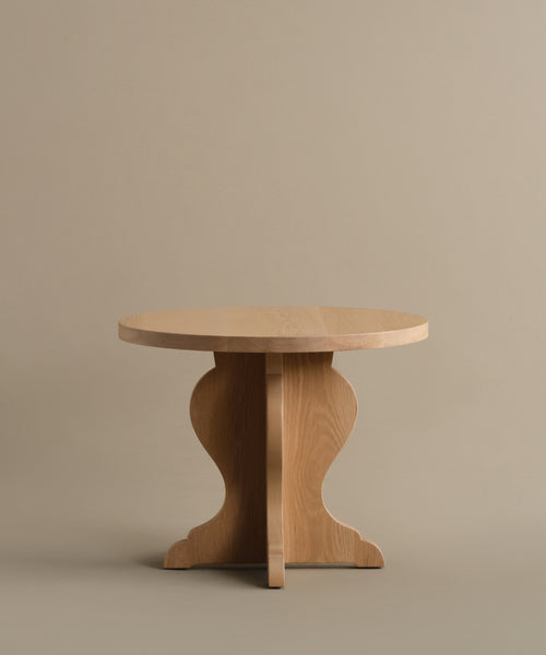 The Lombard Side Table features a vintage-inspired design with a round solid white oak top and curved legs, shown here against a plain beige background.