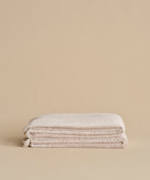 The Loom Bath Sheet, crafted from ultra-soft cotton modal, is neatly folded against a matching plain beige background.