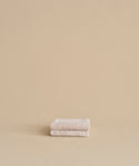 The Loom Hand Towel, made from soft cotton modal in beige, is neatly folded and placed on a matching surface and background, creating a calm and minimalistic look.