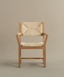 The Montecito Dining Arm Chair has a warm oak frame, clean lines, armrests, and a woven Danish paper cord seat and backrest for a simple modern look.