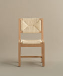 The Montecito Dining Chair features handwoven Danish paper cord on the seat and backrest, a warm oak finish, and clean lines, all set against a plain light brown background.