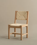 The Montecito Dining Chair showcases a warm oak angular frame and a handwoven Danish paper cord seat and backrest, presented on a plain taupe background.