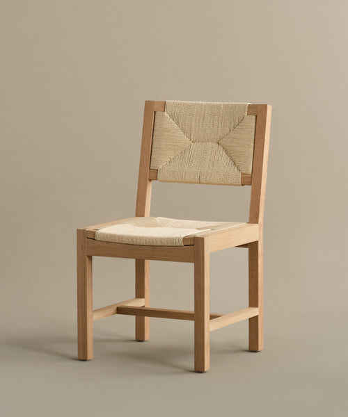 The Montecito Dining Chair showcases a warm oak angular frame and a handwoven Danish paper cord seat and backrest, presented on a plain taupe background.