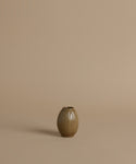 A ribbed ceramic vases with a glossy brown glaze, arranged against a solid beige background.