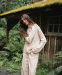 A woman standing outside wearing an ivory sweater with cream jeans. 