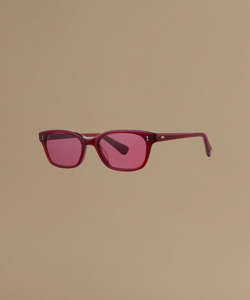Red sunglasses against a beige background.