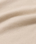 Close-up of the Simone V-Neck in beige, featuring a detailed cotton merino knit with visible texture and soft, wavy folds. Even stitches highlight the luxury quality of this fine layer.