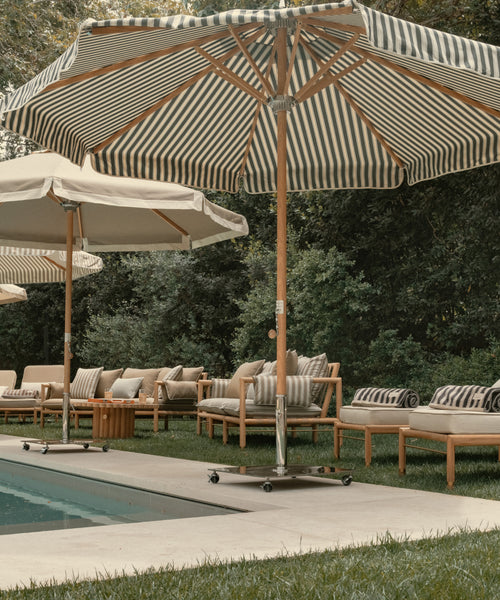 Black and white striped beach umbrella with chairs at a pool