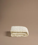 Folded beige cable knit blanket on a brown background