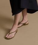 Person wearing olive green sandals on a beige background