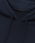 Close-up of the Bay Hoodie in dark navy blue, made from soft brushed fleece, highlighting the hood, drawstrings, collar, and a blank black tag.