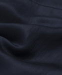 A close-up of smooth, dark navy blue fabric with gentle folds and a soft sheen highlights the Blair Dress’s linen texture and drape—perfect for elevating your spring wardrobe.