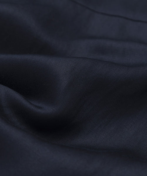 A close-up of smooth, dark navy blue fabric with gentle folds and a soft sheen highlights the Blair Dress’s linen texture and drape—perfect for elevating your spring wardrobe.
