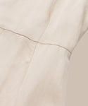 Close-up of light beige fabric with visible seam stitching, showcasing the smooth, slightly textured surface and quality craftsmanship of the Blair Dress—an ideal linen piece for your spring wardrobe.
