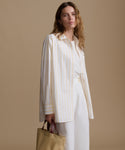 Woman wearing a white and yellow striped shirt with a beige background