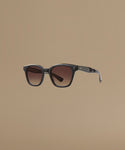 Sunglasses with dark frame and brown gradient lenses on a beige background