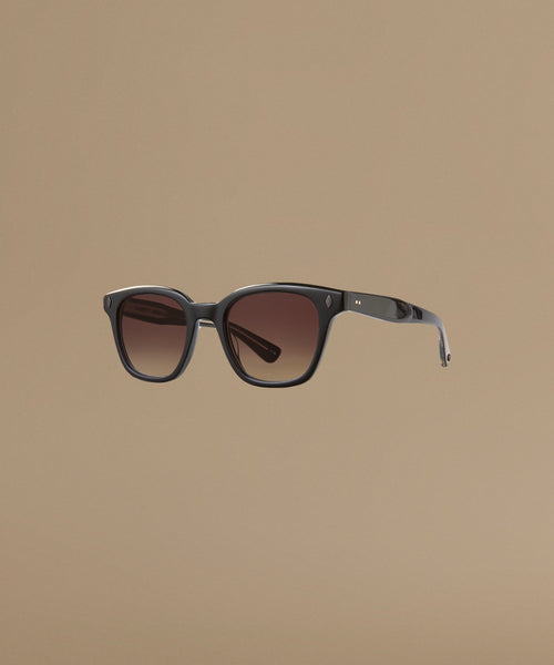 Sunglasses with dark frame and brown gradient lenses on a beige background
