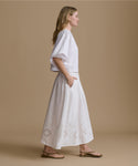 Woman wearing a white top and skirt with cut-out details on a beige background