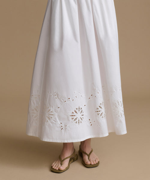 White skirt with intricate cut-out patterns on a beige background