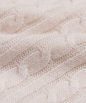 Close-up of the Cable Nell Turtleneck, a soft, light beige sweater featuring a classic cable knit pattern, detailed texture, and subtle boxy silhouette with gentle folds.