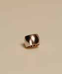 The Campbell Cigar Band, a wide and shiny 14k solid gold ring with a smooth finish, is shown against a plain beige background.