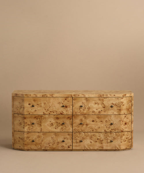 The Carbon Dresser is a six-drawer burlwood piece with soft-close drawers, a light natural finish, and a unique textured grain—ideal for modern bedrooms and shown against a plain beige background.
