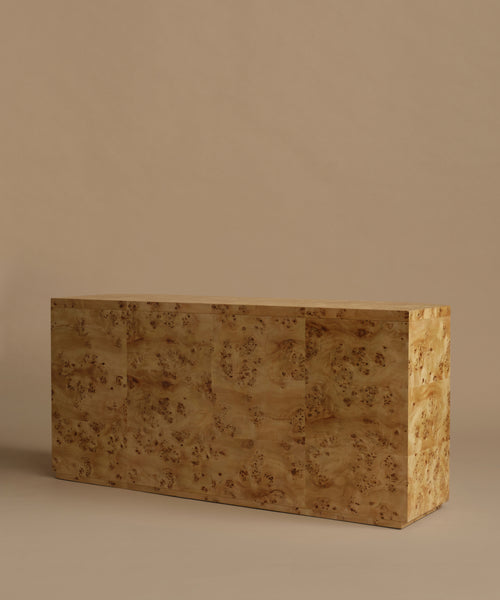 A six-drawer burlwood dresser in warm beige and brown tones, set against a solid beige background.