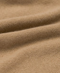 Close-up of the Flynn Cashmere Sweater’s soft, light brown fabric with a smooth, slightly fuzzy texture and gentle folds—evoking cozy comfort.