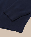 Close-up of the Cashmere Marina Crewneck in navy blue, laid on a beige surface. The ribbed cuffs and hem highlight its fine, soft cashmere texture—ideal as a lightweight, relaxed sweater for spring layering.