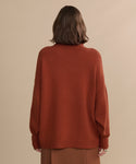 A person with shoulder-length brown hair, seen from behind, wears the Cashmere Porter Turtleneck and a brown skirt, standing against a plain beige background.