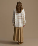 Person wearing a striped sweater and beige pants against a plain background