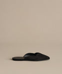 A single Clara Mule in black, featuring a pointed toe and suede finish, is elegantly displayed on a neutral beige background.