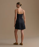 Woman wearing a black Coast dress against a beige background