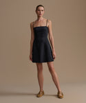 Woman wearing a black Coast Dress against a beige background