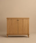 The Coast Hutch is a solid white oak cabinet with vertical slats, two central doors, small black handles, and short angled legs in a mid-century modern hutch design, shown against a beige background.