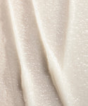 Close-up of the creamy, white texture of Conditioning Lip Balm, with smooth vertical ridges that highlight its thick, nourishing formula spread in layers.