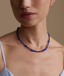 Close-up of a person wearing a lapis Constellation necklace against a neutral background