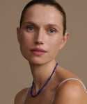 Woman wearing a lapis Constellation necklace against a brown background
