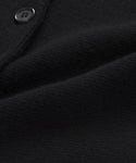 Close-up of the textured black fabric on the Cooper Cardigan, with a visible seam and part of a black button. The soft, slightly folded material highlights the quality finish of this structured cardigan.