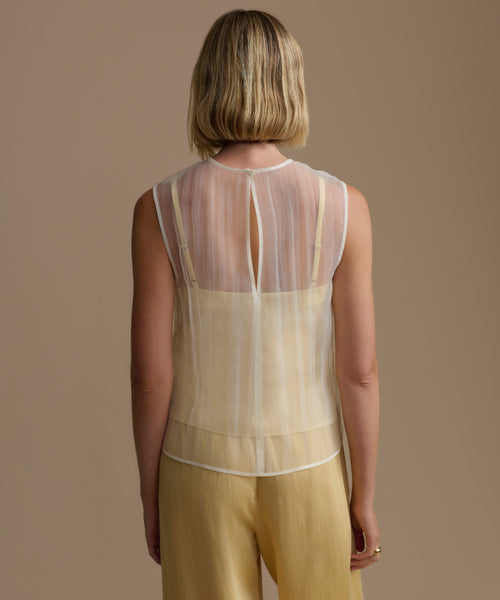Woman wearing a yellow cora top over a beige background
