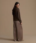 Woman wearing an olive cotton cropped cocoon cardigan and wide-leg pants against a beige background