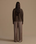Person wearing an olive cotton cropped cocoon cardigan and wide-leg pants against a beige background