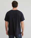 A man with short brown hair stands with his back to the camera, wearing the Mens Vintage Pocket Tee in plain black and blue jeans against a light gray background.